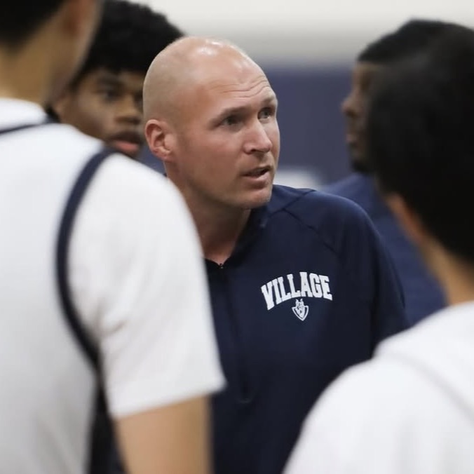 Coach Brandon Christy talking with players in a team huddle